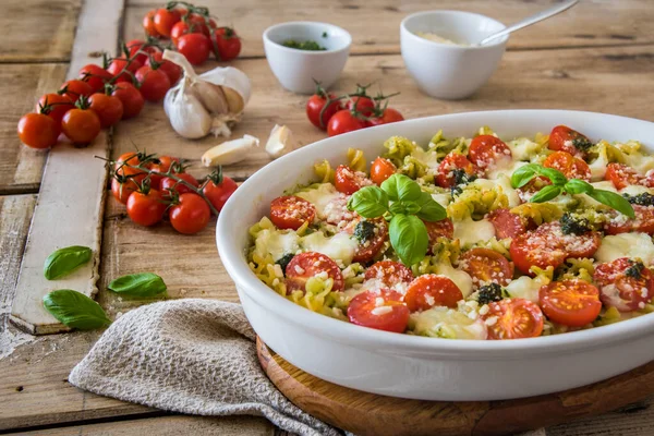 Fesleğen soslu makarna güveci, domates ve mozzarella, vejetaryen, eski ahşap bir masada.