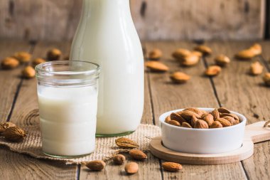 Vejetaryen badem sütü, badem çekirdeği ve eski ahşap bir masada bütün badem.