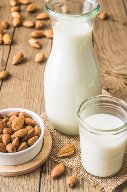 Vejetaryen badem sütü, badem çekirdeği ve eski ahşap bir masada tüm badem.