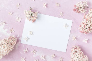 Açık pembe zemin üzerinde pembe leylak çiçekleri olan metin için beyaz kart, kopya alanı ile üst görünüm