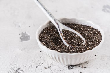 Beyaz zemin üzerinde Chia tohumları olan beyaz kase ve kaşık, kopyalama alanı