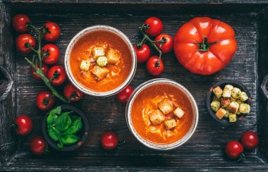 Ahşap zemin üzerinde ahşap bir tepside taze ev yapımı domates çorbası ile dolu iki fincan.
