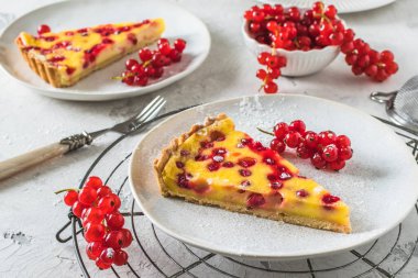 Beyaz arka planda ev yapımı kırmızı frenk üzümü turtası, taze kırmızı üzümle süslenmiş.