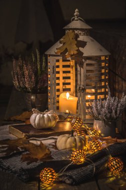 Geceleri veranda ya da veranda beyaz balkabakları, ışıklar ve kuru yapraklar, dikey stok fotoğraf