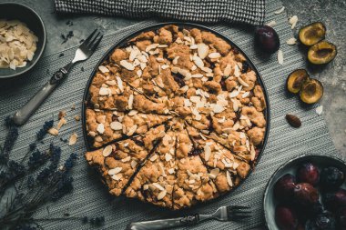 Kavrulmuş bademli tam erik keki, gri arka planda gri bir tabakta parçalara ayrılmış, üst manzara.
