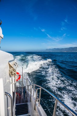Baharda okyanusta seyreden beyaz bir motorlu teknenin parmaklıkları.
