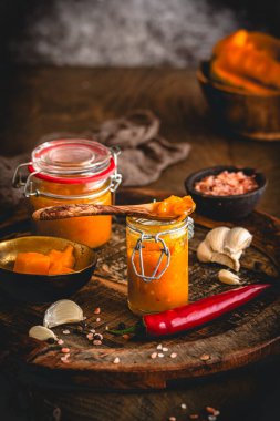 Ev yapımı mango turşusu ve koyu ahşap arka planda malzemeler.