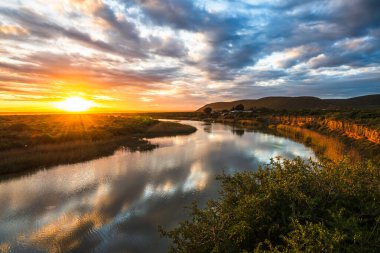 Günbatımında Güney Afrika 'daki Addo Fil Ulusal Parkı' nın güneyindeki bir nehrin manzarası.