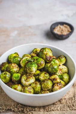 Fırın kavrulmuş Brüksel lahanası beyaz bir kasede, fotokopi alanı ile dikey.