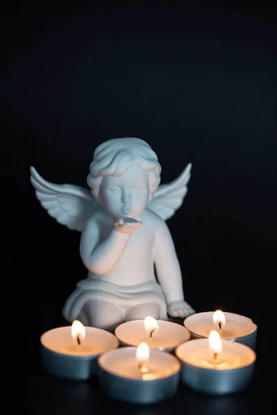 Angel with candles in front of it, black background, mourning card, card, postcard