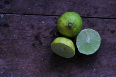Tam limon, yarım limon, ahşap masada bir dilim limon, seçici odaklanma, konuya odaklanma..