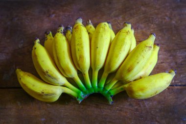 Küçük muz. Taze meyve yemek meşhurdur. Ahşap bir masaya yerleştirilmiş güzel bir aroma.