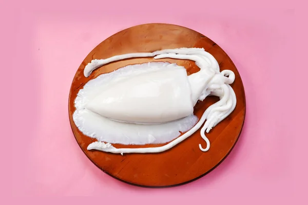 Tahta kesme tahtasında tek bir çiğ mürekkep balığı izole edilmiş. Koonthal.