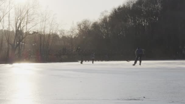 Gelukkige familie wandelen op bevroren rivier ijs. Backlight zon gloeiend en reflecteert in de sneeuw. Winteractiviteiten concept in slow motion. — Stockvideo