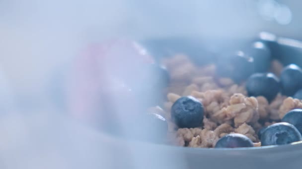 Sliding shot van bessen bosbes en gezonde granola muesli. Gezond ontbijt haver granola met bosbessen, aardbeien en melk. — Stockvideo