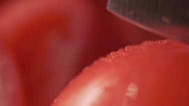 Güzel kırmızı domatesleri mutfak bıçağıyla kesmek, su damlaları makro video. Organik çiftlikten taze ve sağlıklı domates yemek ve pişirmek için.