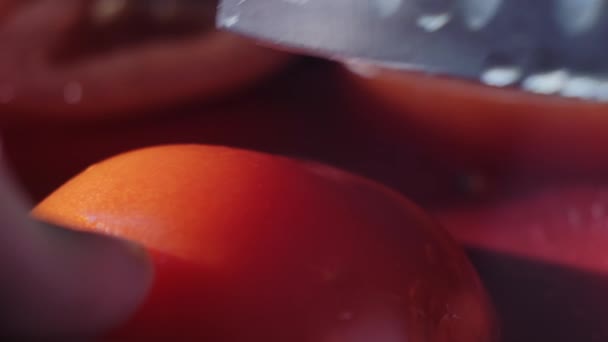 Corte hermoso tomate rojo con cuchillo de cocina, gotas de agua macro video. Tomate fresco húmedo y saludable para comer y cocinar en una granja ecológica — Vídeos de Stock