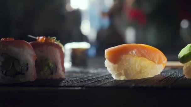 Tiro de close-up deslizante de saborosos rolos de sushi cheios de salmão cru de abacate, enguia. Variedade de tipos sushi com peixe, verduras e arroz. Restaurante Sushi, entrega de comida. Foco seletivo — Vídeo de Stock