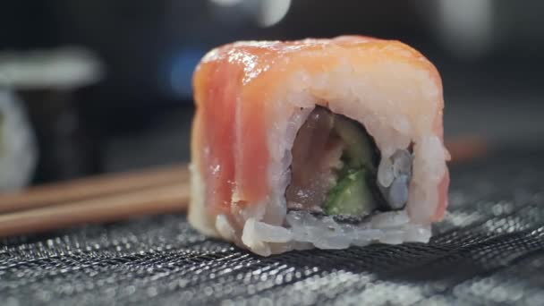 Rolo de sushi saboroso cheio de salmão cru de abacate, atum. Sushi com peixe, legumes e arroz e pauzinhos. Restaurante Sushi, entrega de comida. Foco seletivo — Vídeo de Stock