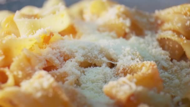 Assiette de pâtes italiennes fraîchement cuites au parmesan. Saupoudrer de petits morceaux de fromage à pâte dure. Gros plan macro shot. — Video