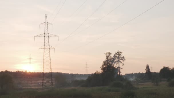 Linee elettriche ad alta tensione al tramonto in estate. Retroilluminazione colpo estivo con fumo e nebbia. — Video Stock