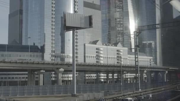 Vista urbana dal finestrino del treno. Costruzioni di ponti con strada con auto. Grattacieli sullo sfondo. — Video Stock