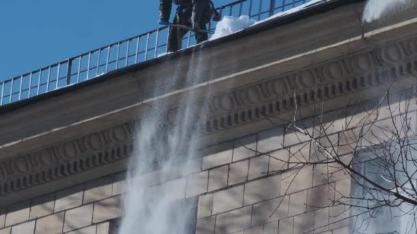 Trabalhadores limpando e despejando neve e gelo de telhados na cidade. Conceito de cidade de inverno — Vídeo de Stock