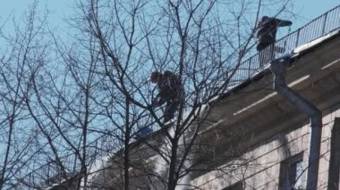 İşçiler şehirdeki çatılardan kar ve buz temizliyor. Kış şehri konsepti