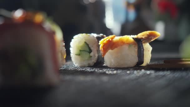 Primer plano de sabrosos rollos de sushi rellenos de salmón crudo de aguacate, anguila. Variedad de tipos de sushi con pescado, verduras y arroz. Restaurante de sushi, reparto de comida. Enfoque selectivo — Vídeos de Stock