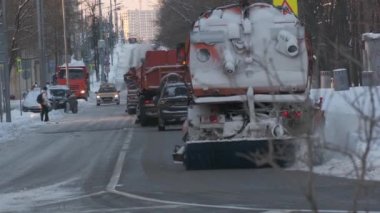 Turuncu şehir kar küreme aracı kışın şehir caddesinde ilerliyor