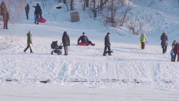 Pessoas diferentes vagam e deslizam no parque montanhoso com neve — Vídeo de Stock