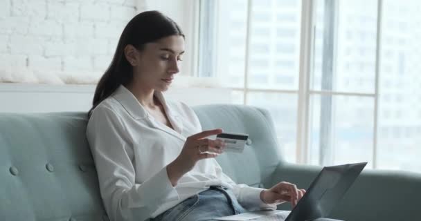 Giovane donna concentrata che utilizza la carta di credito bancaria per pagamenti istantanei e sicuri. — Video Stock