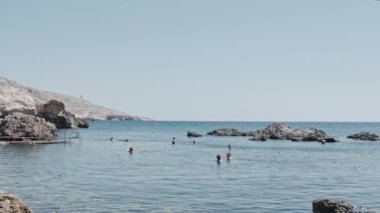 Rahat insanlar turistler sonsuz mavi deniz suyunda yüzerler.