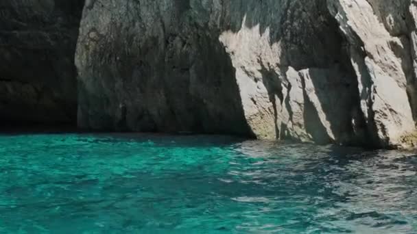 Ruhiges türkisfarbenes Wasser mit kleinen Wellen gegen felsige Klippen — Stockvideo