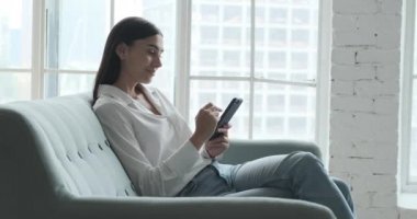 Gülümseyen genç kadın akıllı telefon uygulaması kullanarak olumlu haberler okumaktan zevk alıyor.