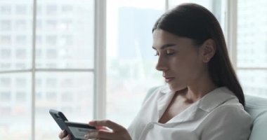 Beyaz bir kadın online alışveriş için kredi kartı ve akıllı telefon kullanıyor..
