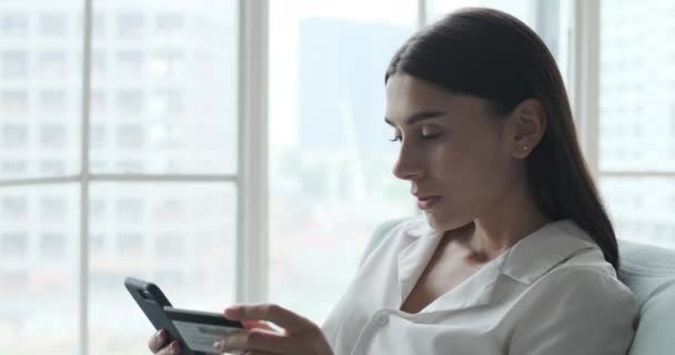 Mujer joven caucásica usando tarjeta de crédito y teléfono inteligente para compras en línea. — Vídeo de stock