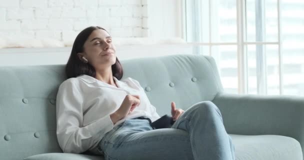 Een mooi meisje luistert naar ontspannende muziek op haar telefoon en raakt opgewonden door de aangename vibes. — Stockvideo