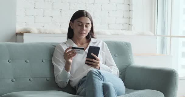 Mujer joven caucásica usando tarjeta de crédito para la aplicación móvil de compras en línea — Vídeo de stock