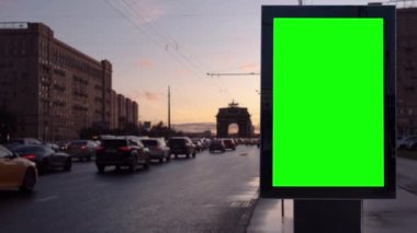 Yoğun bir caddede gün batımına karşı yeşil ekran boş reklam panosu