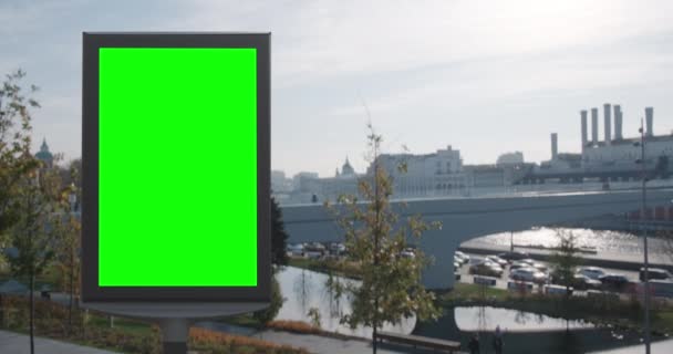 Panneau d'affichage vide avec un écran vert pour la publicité dans le parc sur le magnifique remblai de la rivière, plan ensoleillé d'automne — Video