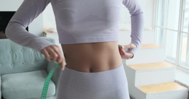 Sportowa dama w sportowej bluzce i legginsach mierzy talię — Wideo stockowe