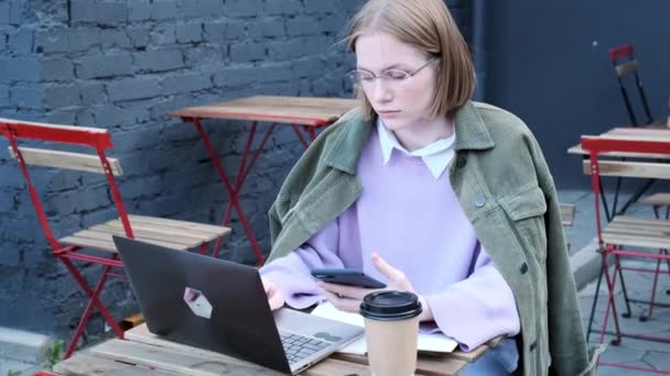 Freelancer jovem se senta no terraço do café no laptop — Vídeo de Stock