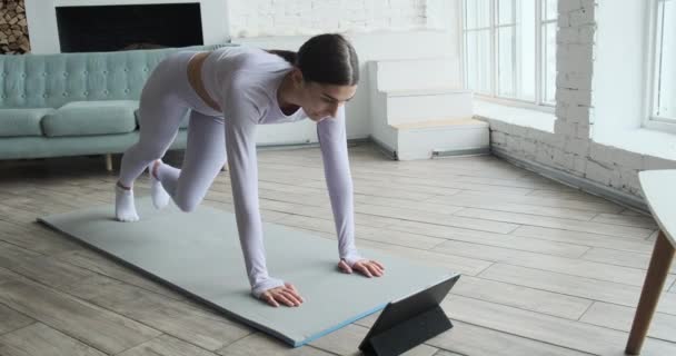 Atletik genç bayan tablette video dersi izliyor. Egzersiz yapıyor.. — Stok video