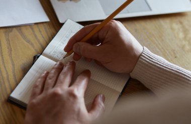 Not defteriyle yazan ve özel ders ile dizüstü bilgisayara bakan adamın görüntüsünü kapat
