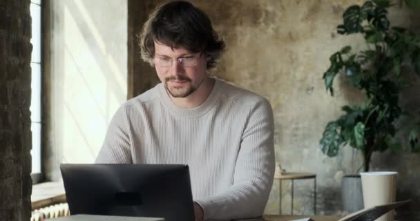 Konzentrierter ernsthafter junger Mann arbeitet von zu Hause aus und genießt ferne Arbeit. — Stockvideo