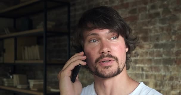 Jovem empresário em casual falando sobre smartphone em casa. — Vídeo de Stock