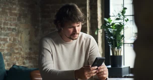 Мобильный человек все время пользуется смартфоном дома — стоковое видео