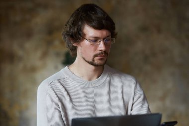 Yoğunlaşmış ciddi genç adam evden çalışıyor ve uzak işten zevk alıyor..