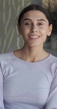 Geniş beyaz dişli gülüşü olan çok çekici bir kadın, şık bir dairede portresi olan. Dikey video.